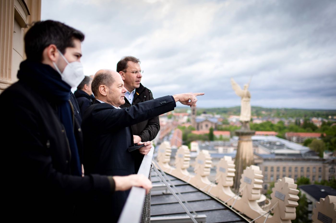 Olaf Scholz steht mit weiteren Personen auf dem Dach der Nikolaikirche und zeigt über Potsdam.